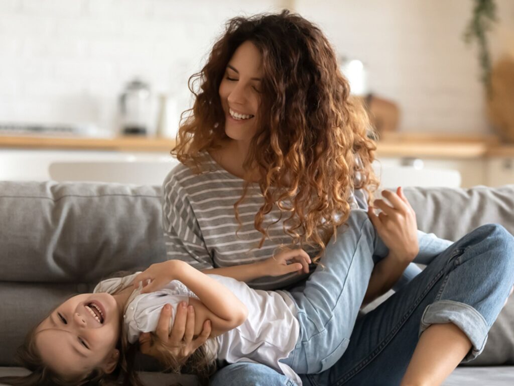 Image of a laughing mother and daughter in their living room